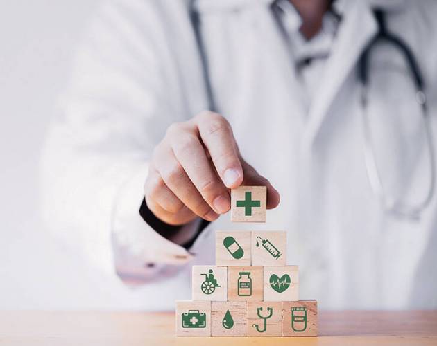Doctor putting and stacking wooden block cube which print screen health care and medical icons for healthy and wellness concept.